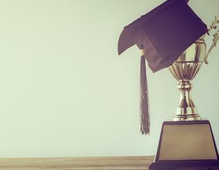 image of trophy with a graduation cap and sunset 